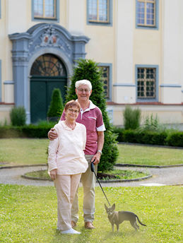 Älteres Paar mit Hund vor Schloss