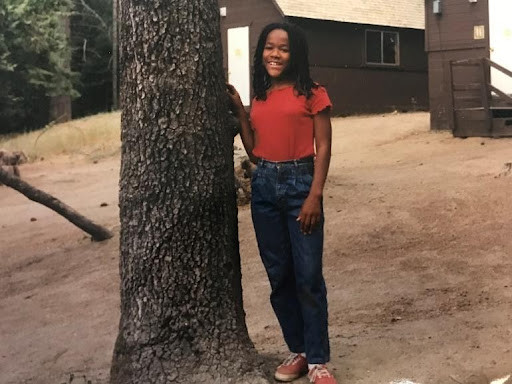 Jamaica Aali standing in front of a cabin at Concordia Language Villages