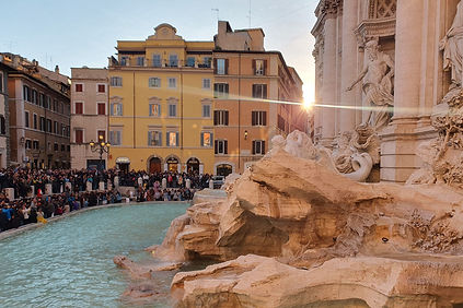 Der Trevi-Brunnen in Rom bei Sonnenuntergang, mit Skulpturen und Wasserspielen in goldenem Abendlicht