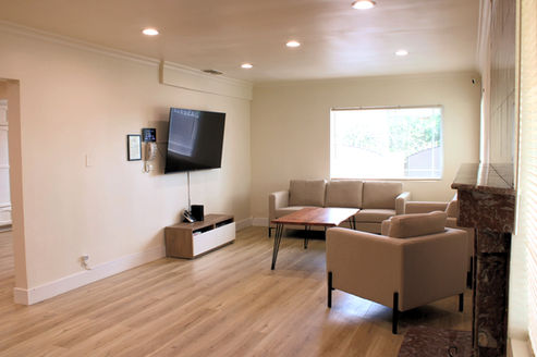 Shared living room at Tranquil Gardens with seating, TV, and open common space.