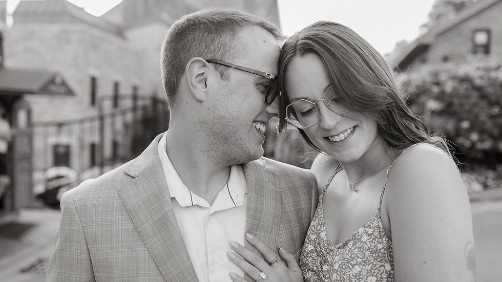 Couple with foreheads together in front of the Elora Mill Hotel & Spa during a surprise proposal session in Elora, Ontario