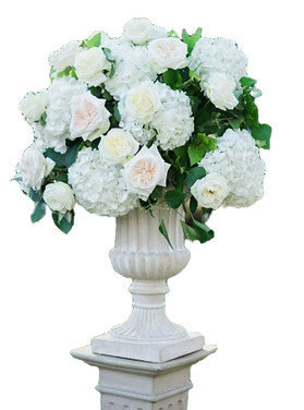 White urn with large floral arrangement of white flowers, greenery, and red accents for wedding ceremony