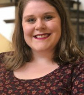 Kirsten is a White female with brown hair wearing a patterned brown shirt. She is presumably sitting in front of a shelf in Greenville, South Carolina.
