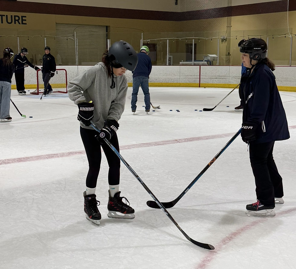 A woman tries out stick handling with advise from a female coach