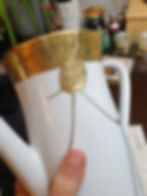 Thumbnail: Kintsugi-reparierte Keramikkaffeekanne, Das goldene Randdekor wurde auch bei der Reparatur beibehalten.