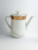 Mit Kintsugi reparierte Teekanne aus Porzellan. Weiß mit goldenem Randdekor, Brüche mit Gold veredelt.