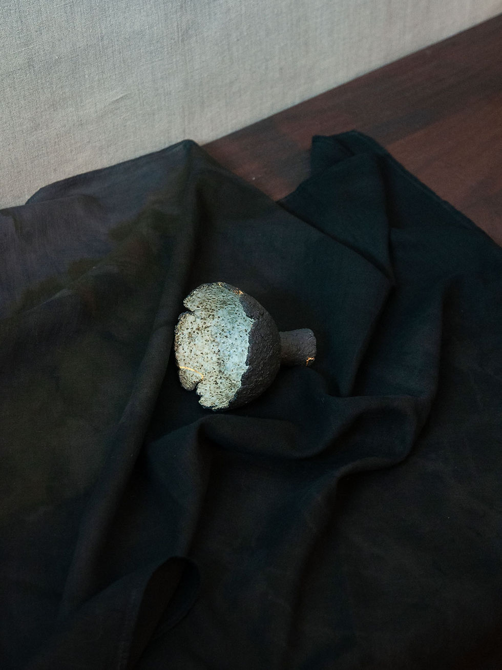 Eine mit der Kintsugi-Technik reparierte Keramikschale. Abgebildet mit einem dunkelblauen Furoshiki-Tuch.