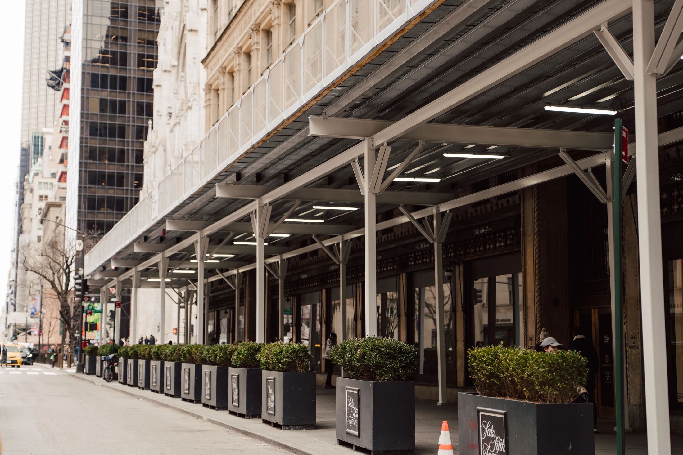 Repeating white steel supports and long storefront perspective at Saks Fifth Avenue