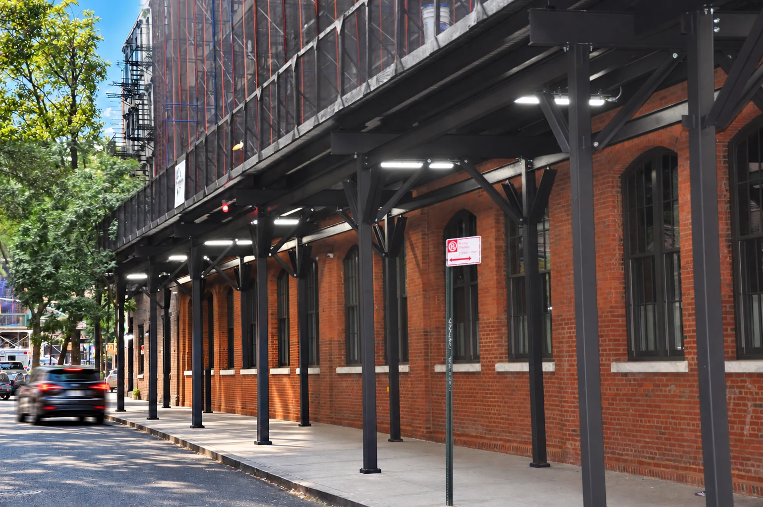 Dark steel supports and pipe scaffolding against historic brick at 36 Bleecker Street