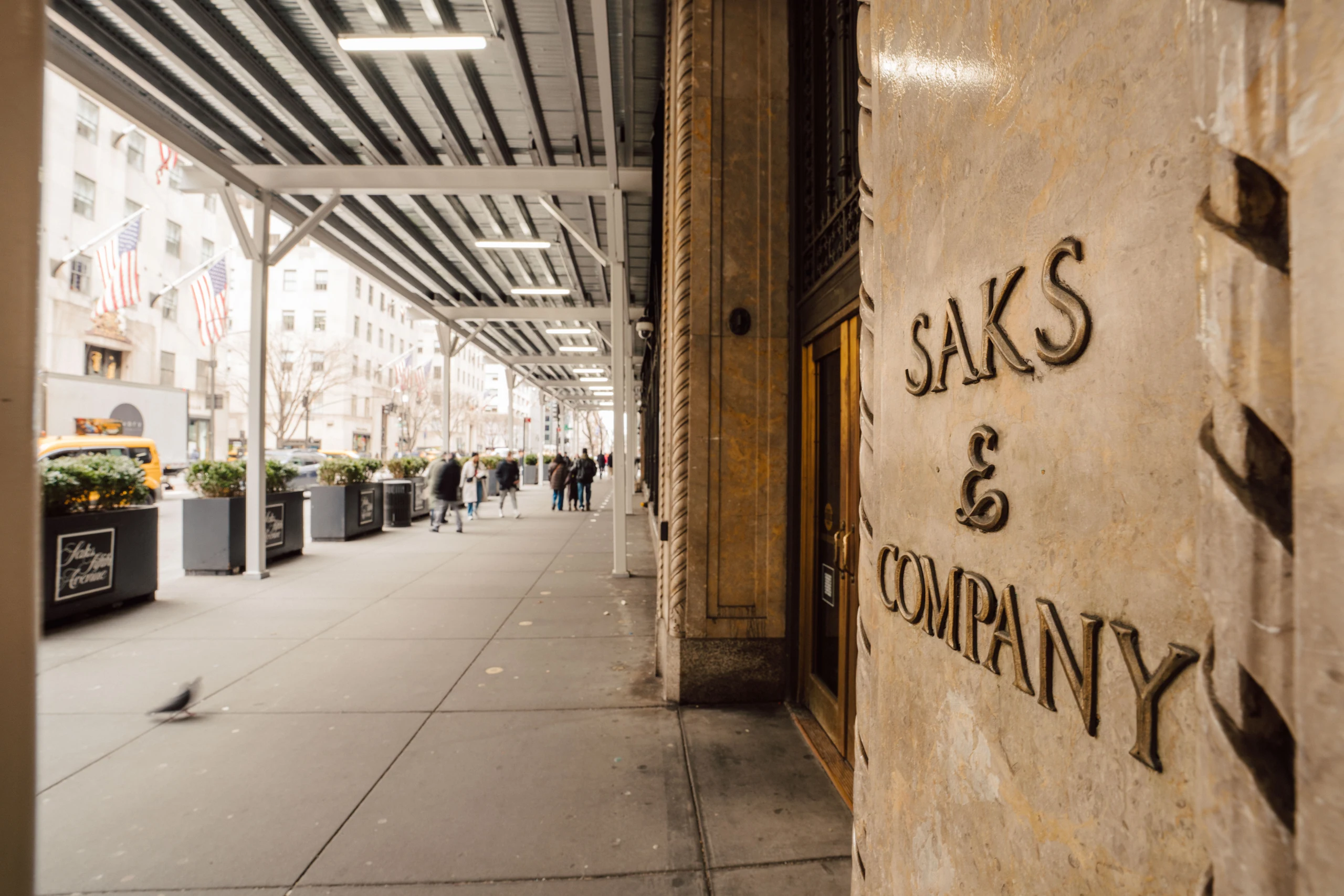 Generous pedestrian space beneath the Saks Fifth Avenue shed, looking along the passage beside the store lettering
