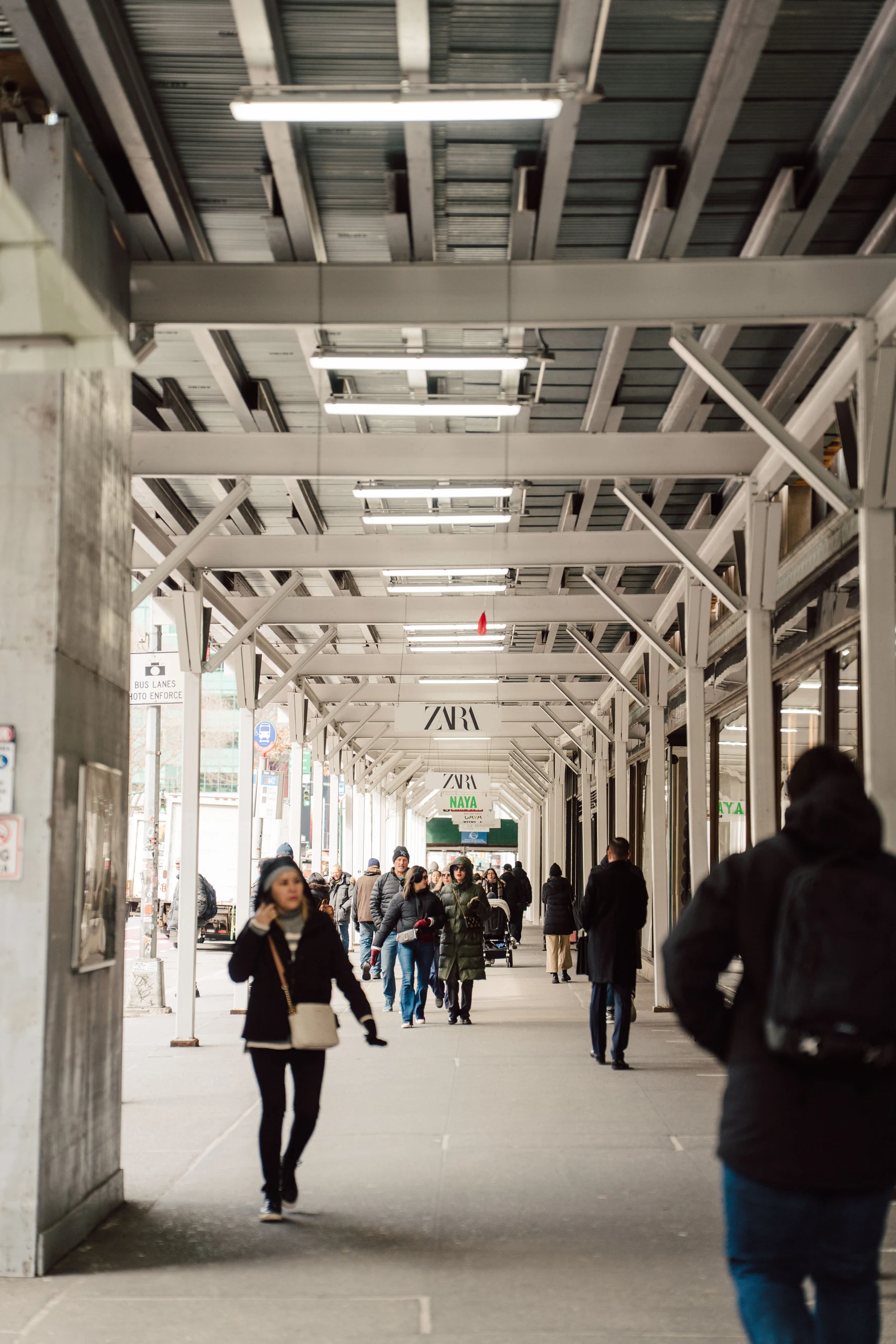 Pedestrians walking through the generous passage beneath Zara's sidewalk shed
