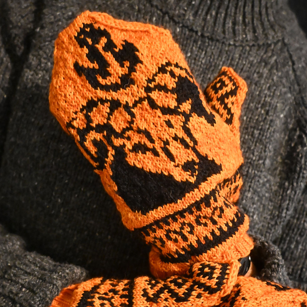 Orange and black Aries mittens worn by model in a grey sweater