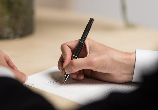 Hand schrijft in wensenboekje met foto op tafel