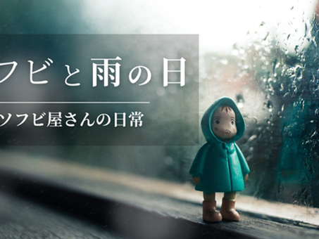 雨に濡れた窓辺に立つレインコート姿のソフビ人形。背景には雨粒が流れ、静かな雰囲気の中で『ソフビと雨の日|ソフビ屋さんの日常』の文字が添えられている。