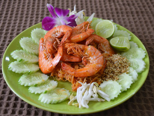 Close-up of Pad Mee Kati, a Southern Thai Prawn Pad Thai with prawns, rice vermicelli, sliced cucumber, peanuts, lime and orchid.
