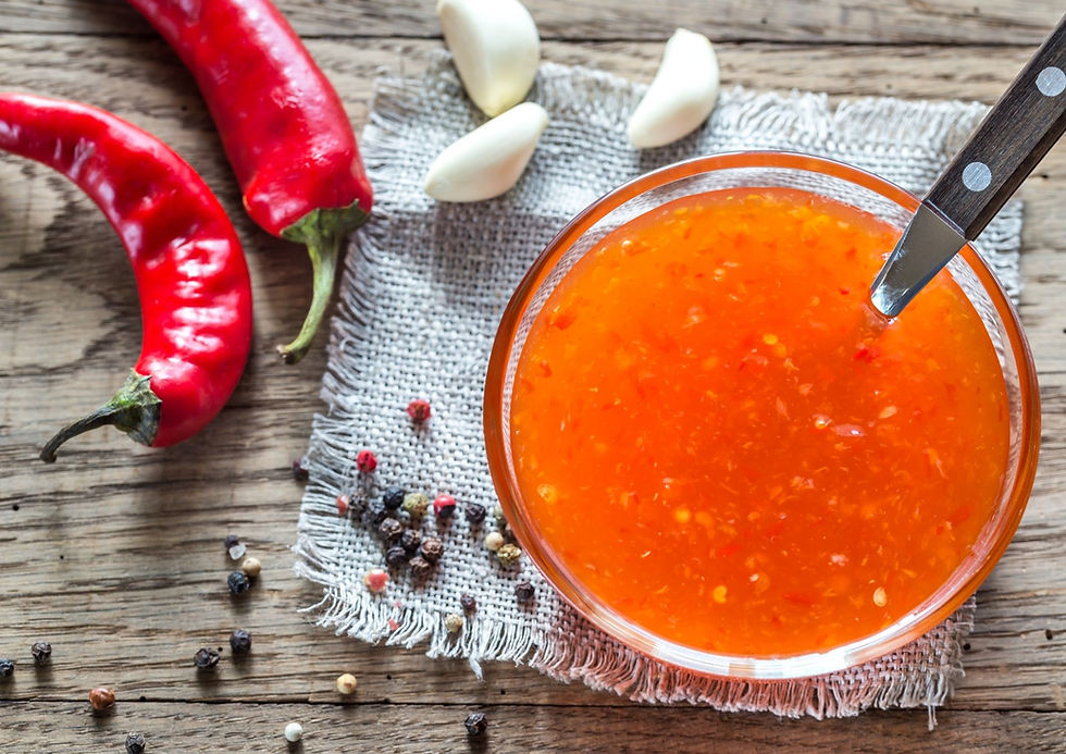 Chilli sauce in a bowl on a table with garlic and fresh chillies