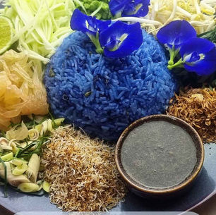 Salade de riz aux herbes thaïlandaise Khao Yam Nam Budu, riz bleu aux fleurs de pois papillon accompagné d’herbes aromatiques, zestes de kaffir, noix de coco rôtie et sauce budu, spécialité du Sud de la Thaïlande.
