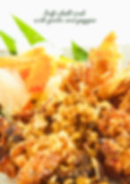 Close-up of golden fried soft-shell crab with garlic and pepper, served with crispy fried garlic and colorful vegetable garnishes.