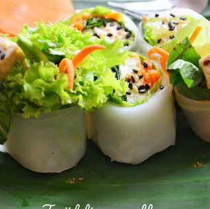 Nahaufnahme von thailändischen Frühlingsrollen mit Gemüse und Tofu, dekoriert mit Sesam und frischen Kräutern.