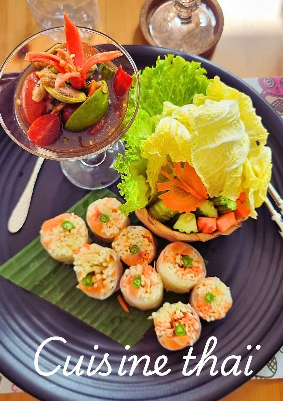Salade de papaye déstructurée avec sauce som tam servie séparément, rouleaux de légumes en feuille de riz et légumes frais disposés sur une assiette, illustrant une présentation moderne de la cuisine thaïlandaise.