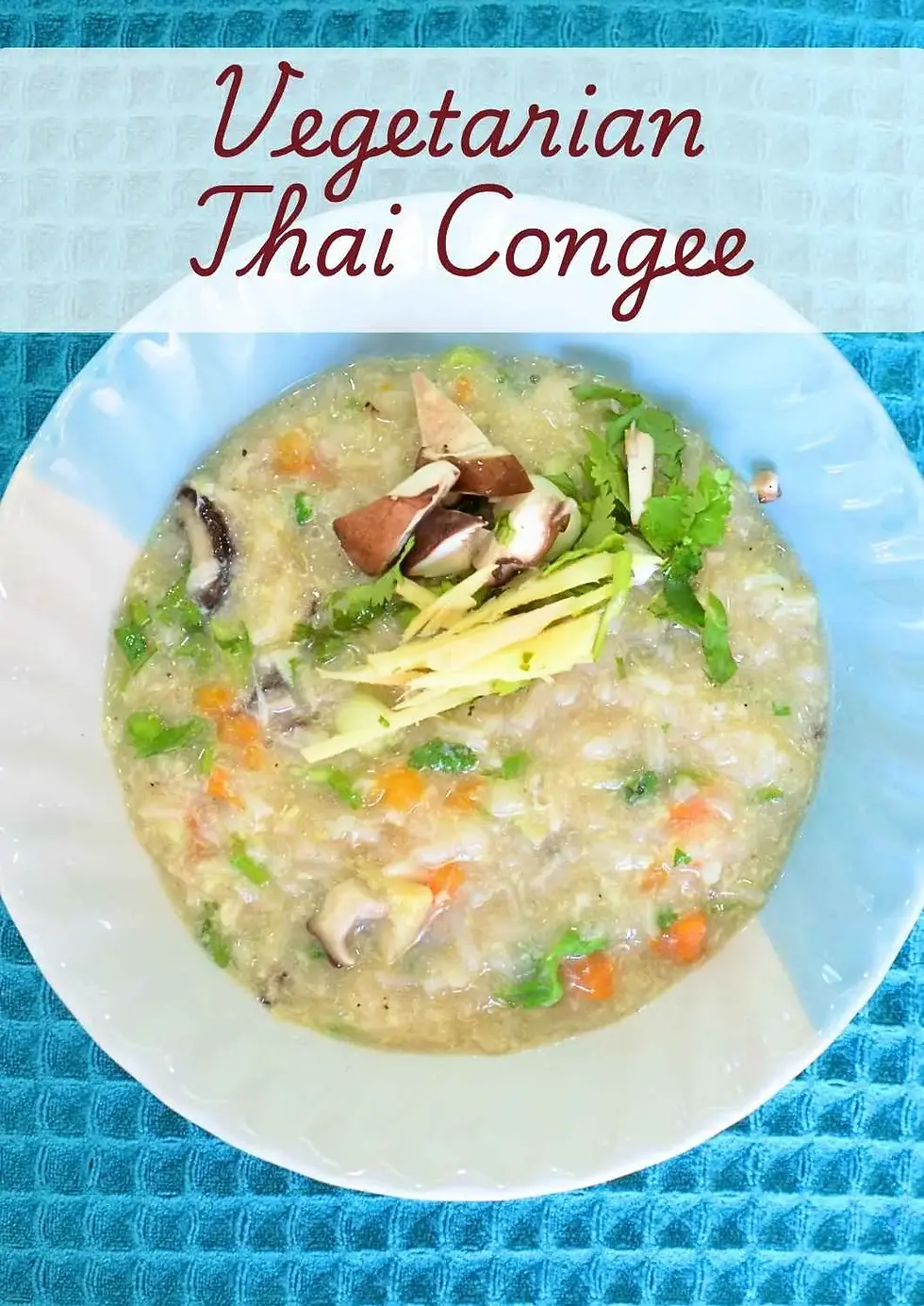 Bowl of vegetarian Thai congee with eggs, topped with shiitake mushrooms, julienned ginger, coriander and spring onions, served in a ceramic bowl on a blue cloth.