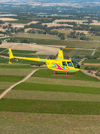 Helicopter flying over scenic Barossa Valley vineyards, highlighting breathtaking aerial views of South Australia’s renowned wine region during an unforgettable helicopter tour from Adelaide.