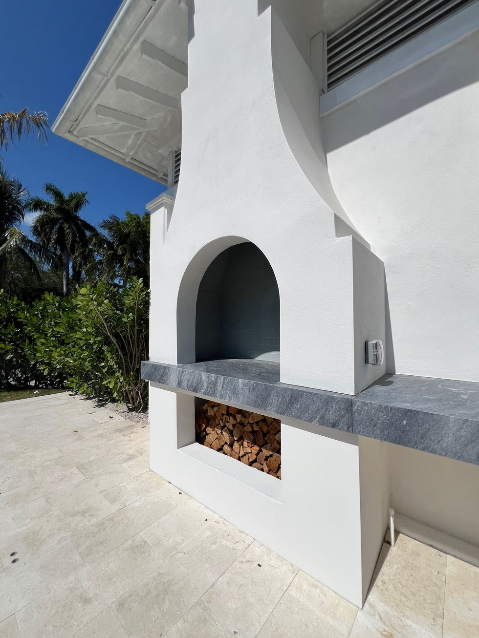 a white building with a built in fireplace and a shelf filled with logs