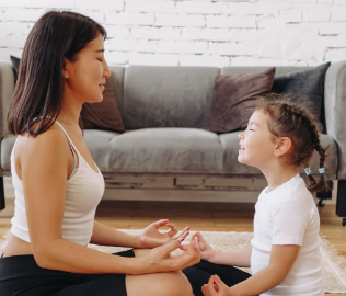 A woman and child meditate together at home.