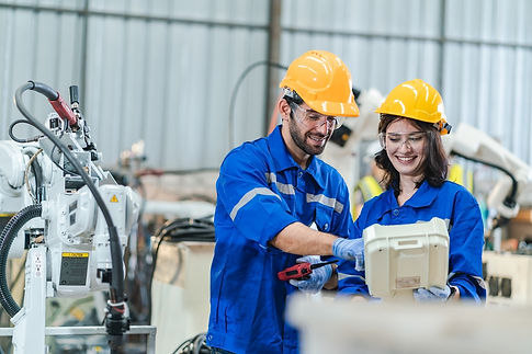 Two engineers in blue uniforms collaborating with factory automation equipment.