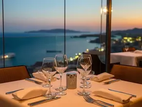 Elegant fine dining table setup overlooking the Mediterranean coastline in North Cyprus, featuring soft lighting, premium glassware, and a luxury restaurant ambience.