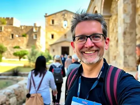 A licensed tourist guide leading visitors through Bellapais Abbey in North Cyprus, wearing an official TRNC tourist guide ID card.