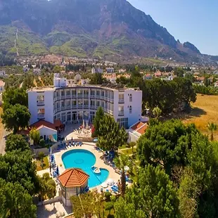 Sempati Hotel coastal swimming pool with mountain and sea backdrop.