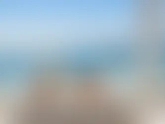 A sunlit seaside terrace in Kyrenia with a white linen table set for breakfast — croissants, fruit, smoked salmon, and two glasses of Champagne glimmering in the morning light. The turquoise sea sparkles in the background beneath clear blue skies.