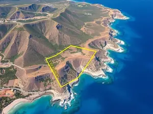 Aerial view of a coastal land plot in North Cyprus overlooking the Mediterranean, with mountains in the background and marked boundaries
