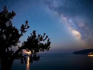 The Night Sky of North Cyprus showing a golden sun touching the sea as it reaches sunset and a sky full of stars and glittering galaxies.