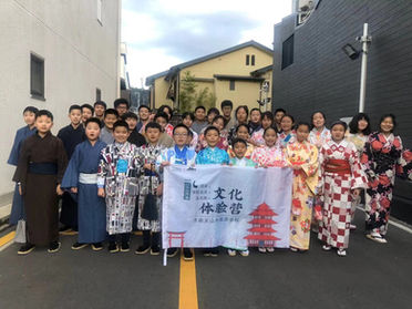 Chinese students in traditional Japanese clothing pose with a banner
