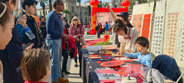 Child showcasing Chinese calligraphy at a outdoor event