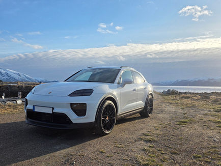 Porsche Macan 4 Electric i vit lack fotograferad snett framifrån med svarta detaljer, stora RS Spyder-fälgar och sportig SUV-profil.