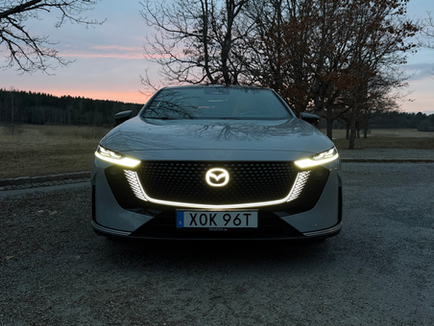 Mazda6e Takumi Plus fotograferad framifrån med smala strålkastare, modern frontdesign och tydlig premiumkänsla.