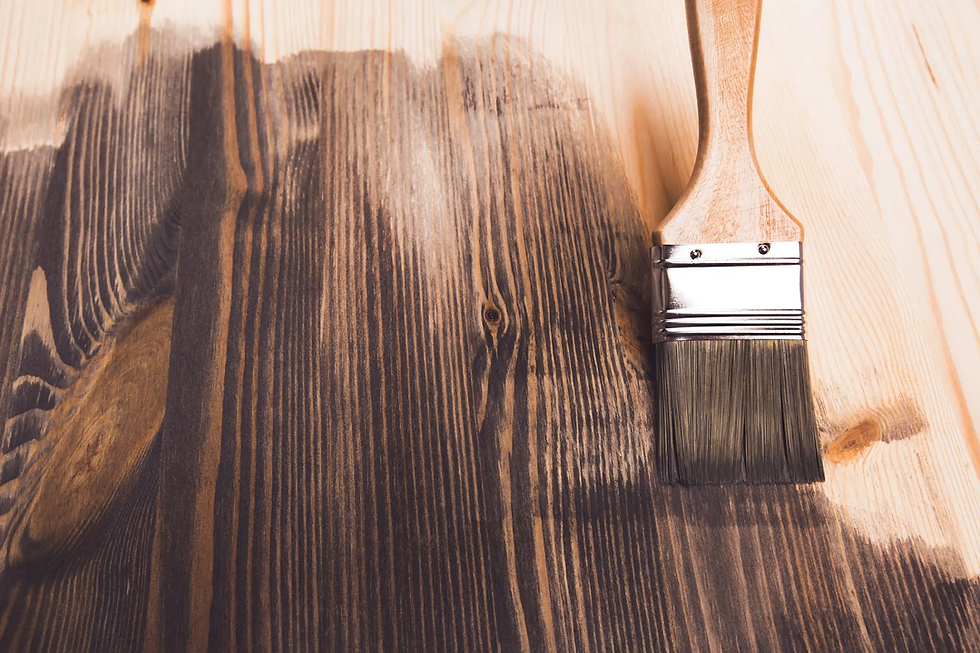 Paintbrush staining wood with dark varnish, highlighting wood grain. Contrast between stained and natural wood creates a satisfying effect.