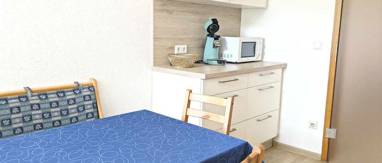 Moderne, voll ausgestattete Ferienwohnungsküche mit Cerankochfeld, Backofen, Kühlschrank mit Gefrierfach, Geschirrspüler, Waschmaschine, Mikrowelle, Kaffeemaschine, Pad-Maschine, Wasserkocher, Rührgerät und Küchenutensilien.