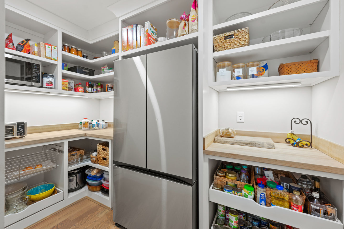 Organized pantry with shelves and stainless steel refrigerator.