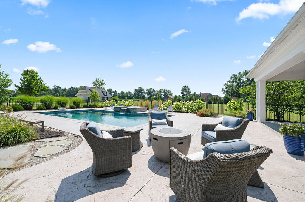 Outdoor patio with chairs overlooking a pool.