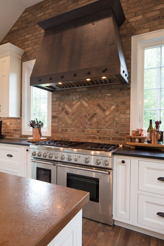 Modern kitchen with brick backsplash and stainless steel stove.