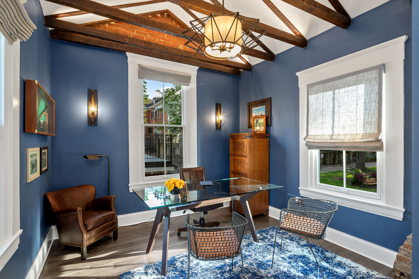 Modern office with blue walls and wooden ceiling beams.