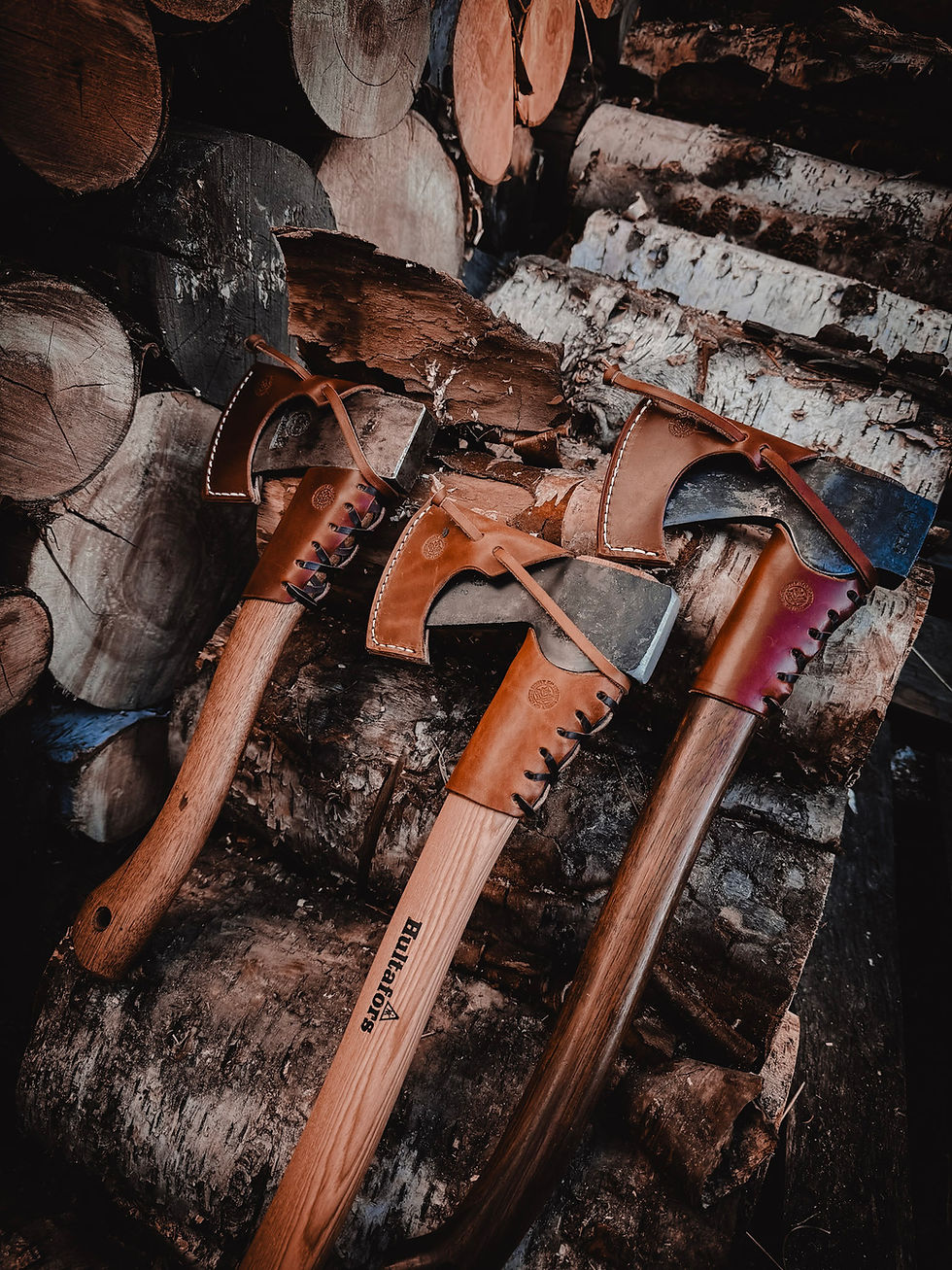 axes with overstrike collars and sheaths on a birch log pile