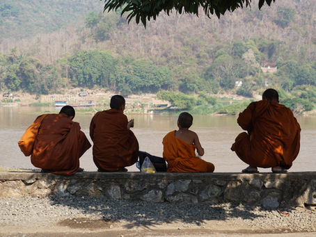 Monniken die rusten in de schaduw aan de rivier in Luang Prabang