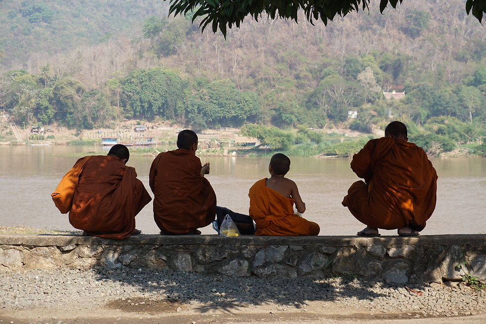 Monniken die rusten in de schaduw aan de rivier in Luang Prabang