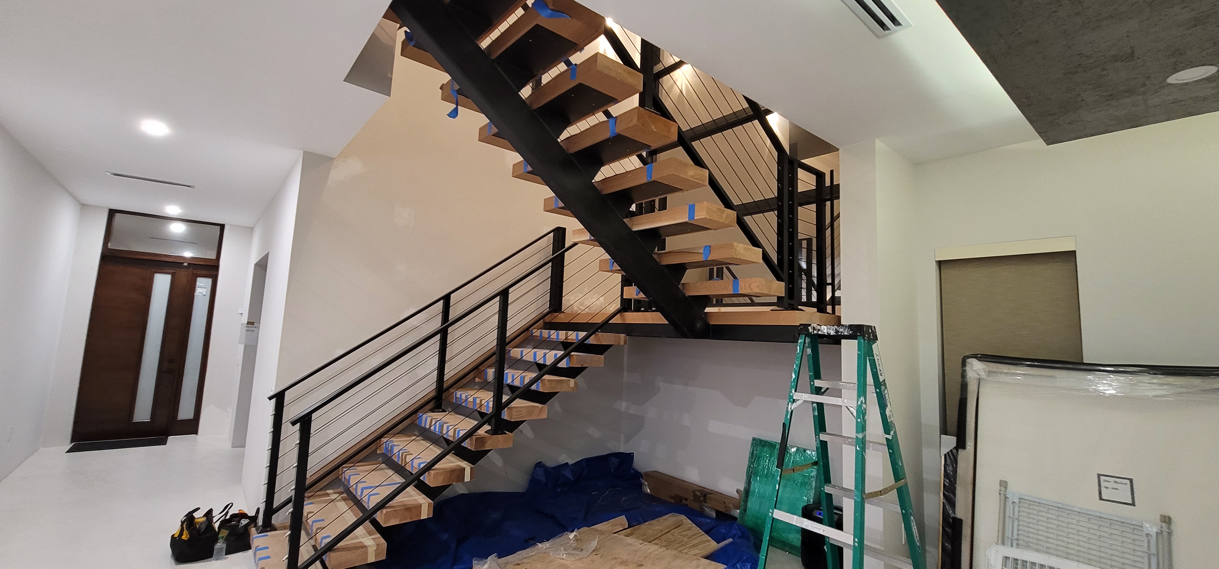 Steel stair stringer being installed with wood treads and cable rail