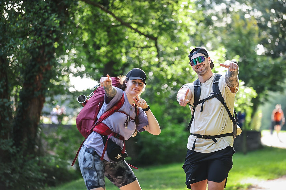 Teilnehmerin und Teilnehmer mit Sportbrille zeigen lachend in die Kamera beim Megamarsch